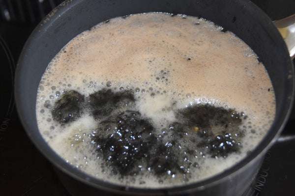 Pan showing niger seed being boiled to make fishing bait.