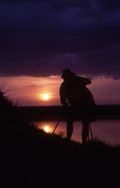 Photograph taken at sunset next to lake with camera on a tripod looking towards the sunset